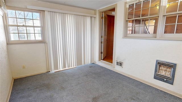 carpeted spare room featuring a textured wall, visible vents, and heating unit