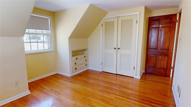 additional living space with lofted ceiling, baseboards, and wood finished floors