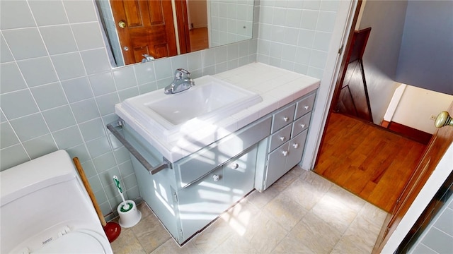 bathroom featuring decorative backsplash, vanity, and tile walls