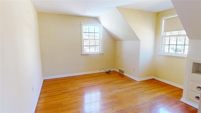 additional living space featuring lofted ceiling, visible vents, baseboards, and wood finished floors