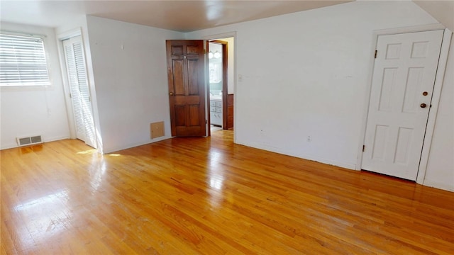 unfurnished room featuring light wood-style flooring, visible vents, and baseboards