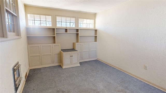 interior space featuring carpet floors, a textured wall, and baseboards