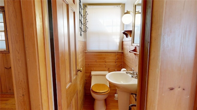 bathroom with a sink, toilet, and wooden walls