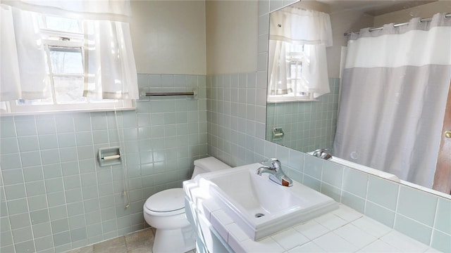 full bath with a shower with curtain, a sink, toilet, and tile walls