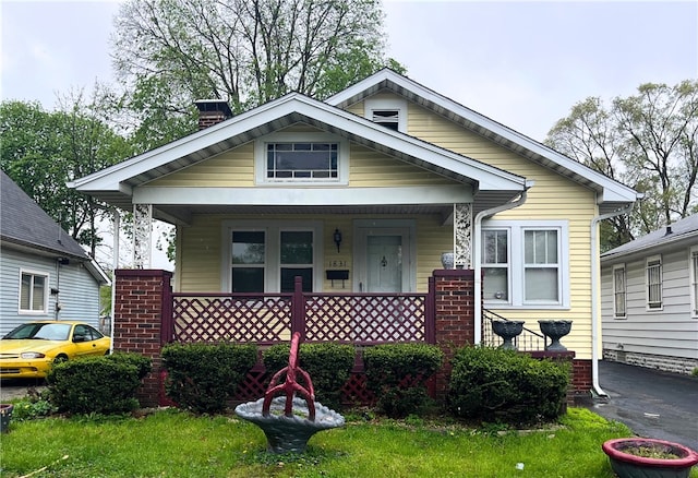 view of front facade with covered porch and a chimney