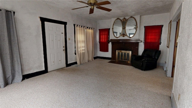 living area featuring carpet flooring, a textured ceiling, a ceiling fan, and a fireplace
