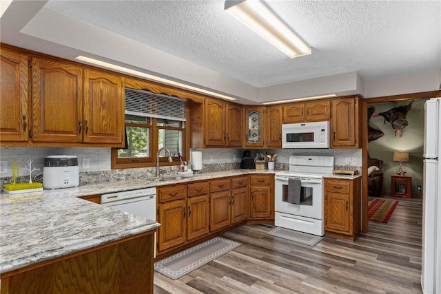 18058 E 1545th Ave, Teutopolis, IL 62467 - kitchen featuring white appliances, brown cabinets, a textured ceiling, wood finished floors, and light stone counters