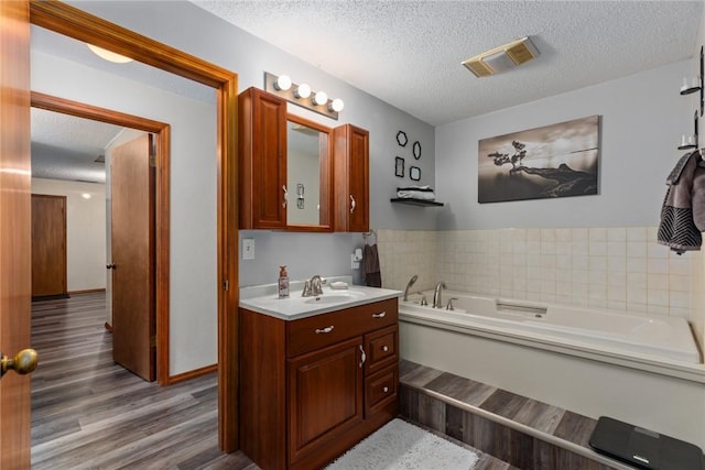 18058 E 1545th Ave, Teutopolis, IL 62467 - bathroom featuring vanity, wood finished floors, a garden tub, and a textured ceiling