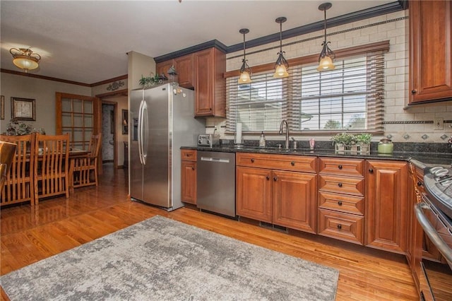 kitchen featuring brown cabinets, ornamental molding, decorative light fixtures, stainless steel appliances, and light wood-style floors