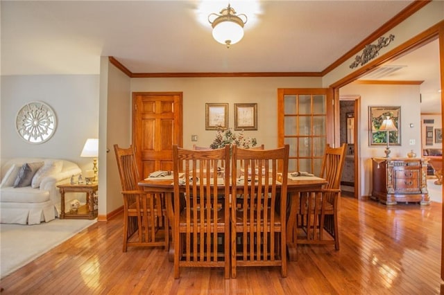 dining area with baseboards, hardwood / wood-style floors, and crown molding