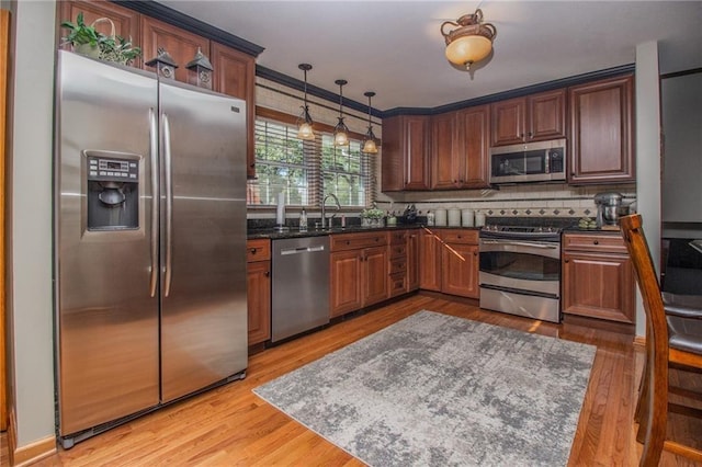 kitchen with decorative backsplash, a sink, light wood-style floors, and stainless steel appliances