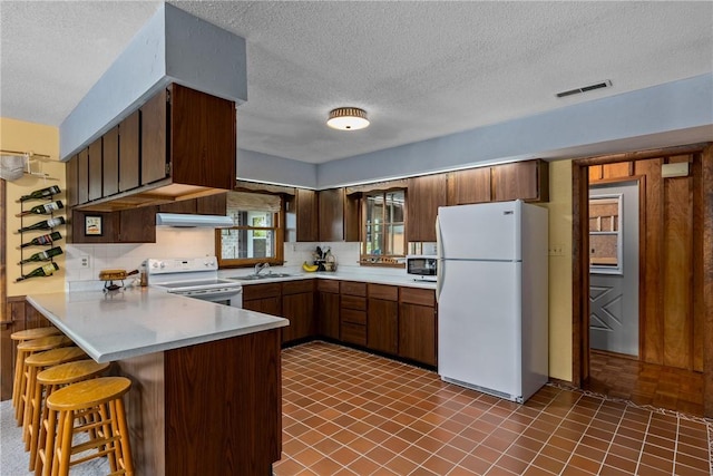14915 N 8th Ave, Effingham, IL 62401 - kitchen featuring white appliances, under cabinet range hood, a peninsula, a textured ceiling, and light countertops
