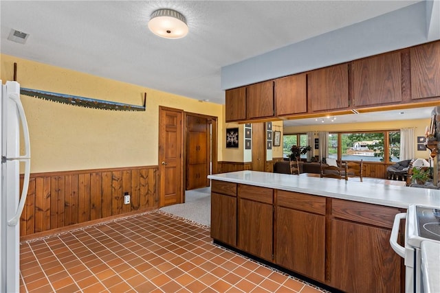 14915 N 8th Ave, Effingham, IL 62401 - kitchen with white appliances, wainscoting, light countertops, brown cabinetry, and wood walls