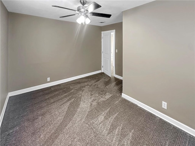 empty room featuring visible vents, baseboards, dark colored carpet, and a ceiling fan