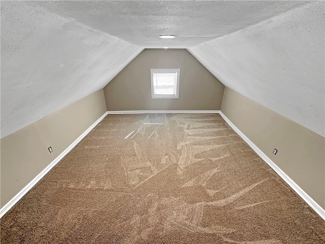 bonus room featuring lofted ceiling, carpet flooring, a textured ceiling, and baseboards