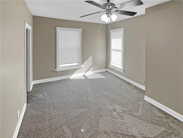 carpeted spare room featuring baseboards and a ceiling fan