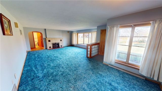 unfurnished living room featuring a fireplace, carpet, and a baseboard radiator