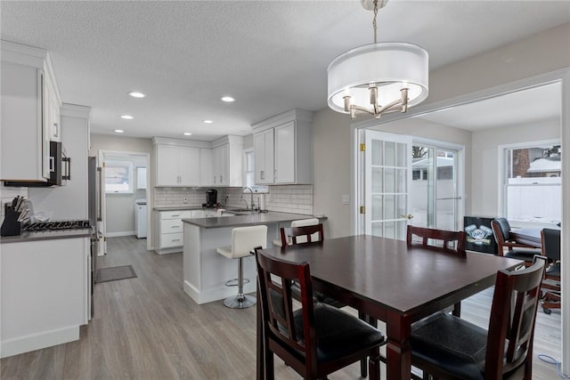 dining space featuring light wood finished floors, recessed lighting, washer / clothes dryer, a textured ceiling, and baseboards