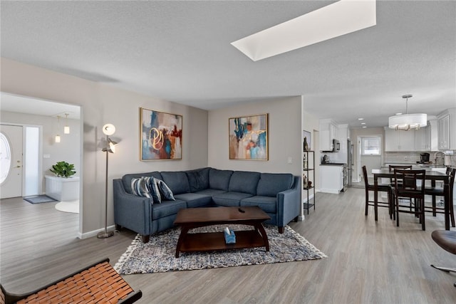 living area with light wood finished floors, baseboards, and a textured ceiling