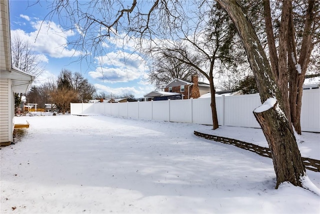 yard covered in snow featuring fence