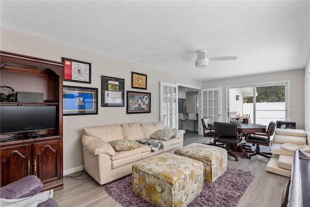 living room with baseboards, a ceiling fan, and light wood-style floors