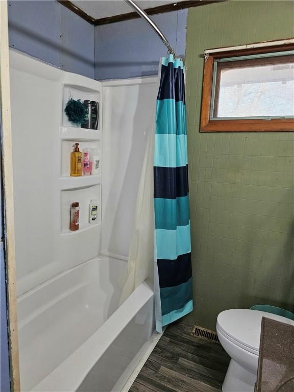 bathroom with hardwood / wood-style flooring, toilet, and shower / bath combo