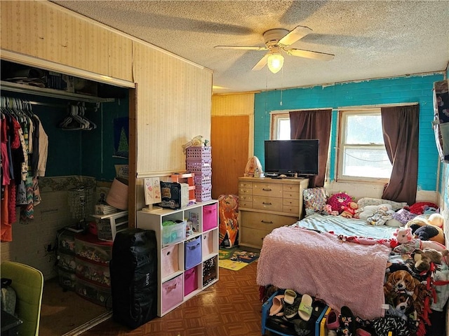 bedroom featuring dark parquet flooring, ceiling fan, a textured ceiling, and a closet