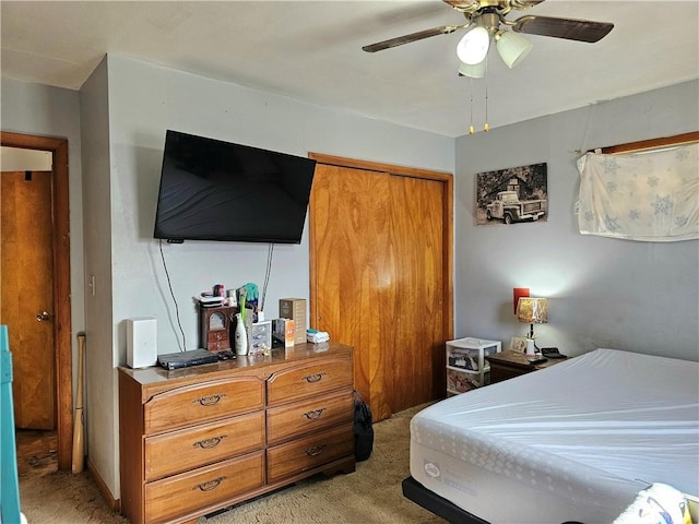 bedroom featuring light colored carpet, ceiling fan, and a closet