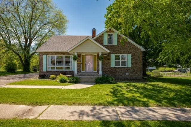 bungalow-style home featuring a front lawn and a chimney