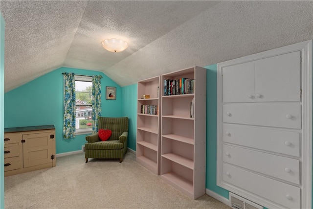 sitting room featuring light carpet, a textured ceiling, lofted ceiling, and baseboards