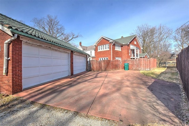 exterior space with a garage, fence, and brick siding