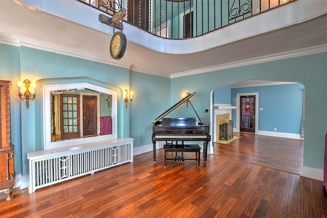 sitting room with baseboards, ornamental molding, and wood finished floors