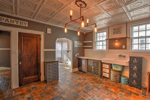 unfurnished office with stone tile floors, baseboards, arched walkways, an ornate ceiling, and a sink