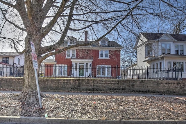 view of front facade with a fenced front yard, a chimney, and brick siding