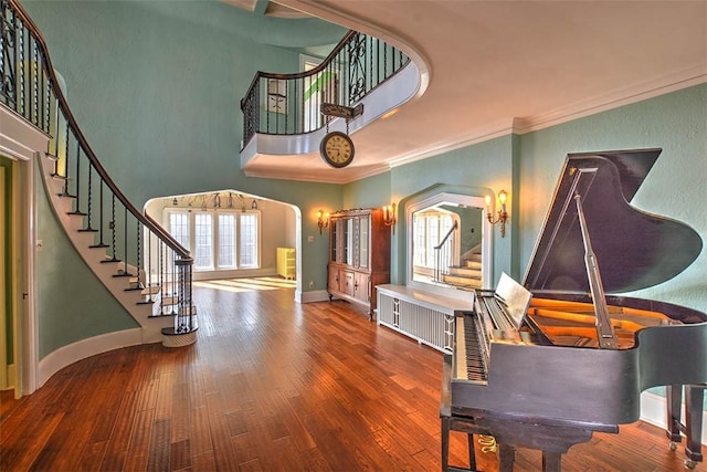 foyer featuring wood finished floors, a towering ceiling, baseboards, ornamental molding, and stairway