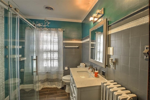 bathroom featuring visible vents, vanity, tile walls, ornamental molding, and radiator heating unit