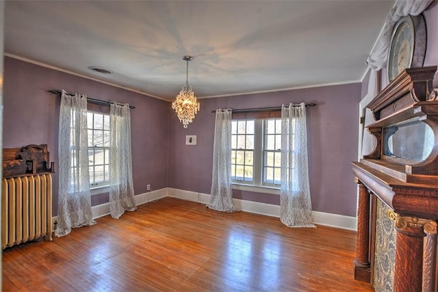 unfurnished dining area with ornamental molding, radiator heating unit, wood finished floors, and visible vents