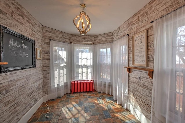 interior space with stone finish floor, radiator, and a notable chandelier