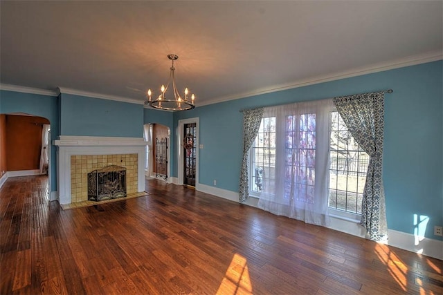 unfurnished living room with baseboards, arched walkways, dark wood-style flooring, and a tile fireplace