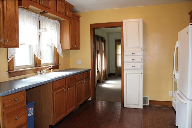707 W N 2nd St, Shelbyville, IL 62565 - kitchen with freestanding refrigerator, brick patterned floors, brown cabinetry, a sink, and dark countertops
