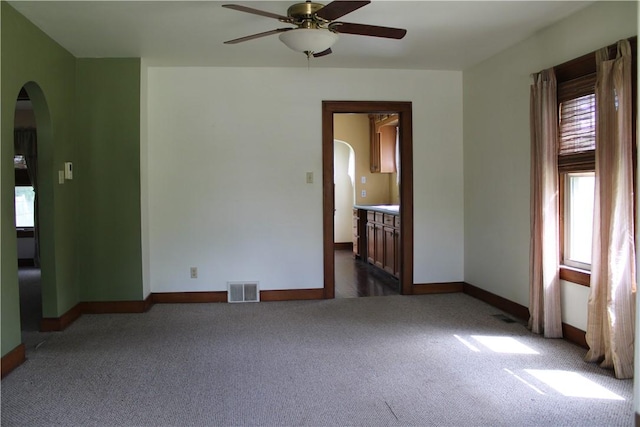 707 W N 2nd St, Shelbyville, IL 62565 - unfurnished room featuring arched walkways, dark carpet, a ceiling fan, and healthy amount of natural light