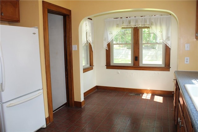 707 W N 2nd St, Shelbyville, IL 62565 - unfurnished dining area featuring brick floors, baseboards, and arched walkways