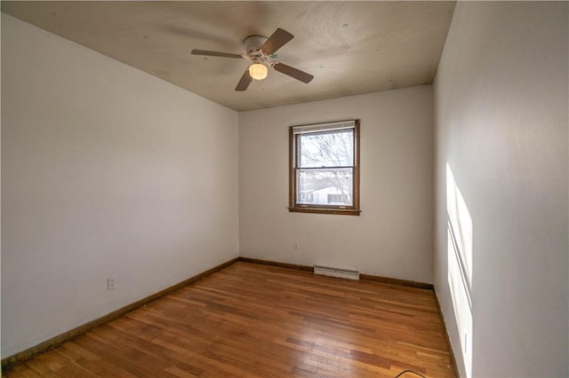 empty room with ceiling fan, hardwood / wood-style floors, and a baseboard heating unit