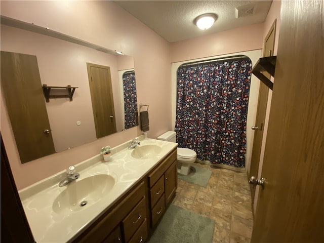 bathroom with visible vents, a sink, toilet, and double vanity