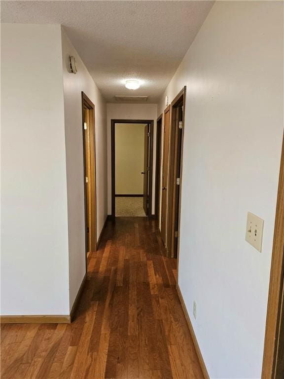 corridor with dark wood-type flooring and a textured ceiling