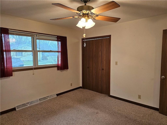 unfurnished bedroom featuring ceiling fan, a closet, carpet floors, and a textured ceiling