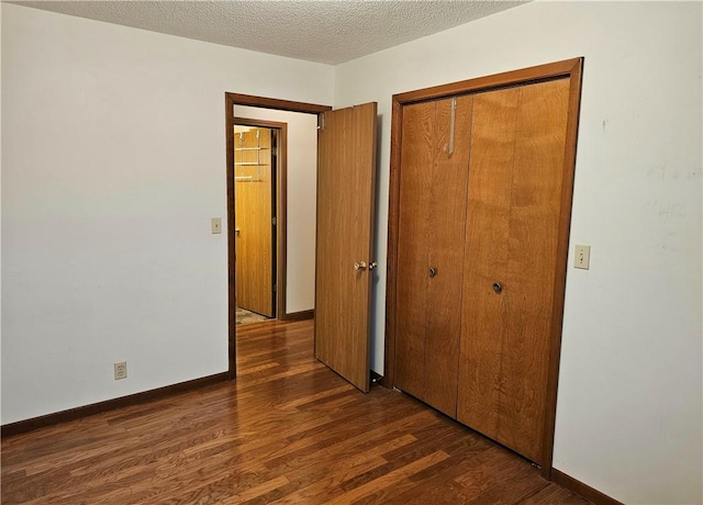 unfurnished bedroom featuring a textured ceiling, a closet, and dark hardwood / wood-style floors