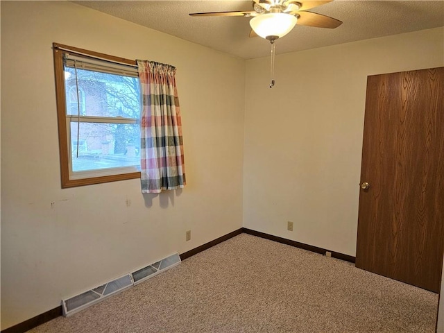 carpeted spare room featuring ceiling fan and a textured ceiling