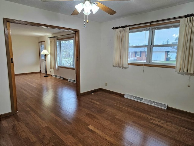 empty room featuring a textured ceiling, dark hardwood / wood-style flooring, and ceiling fan