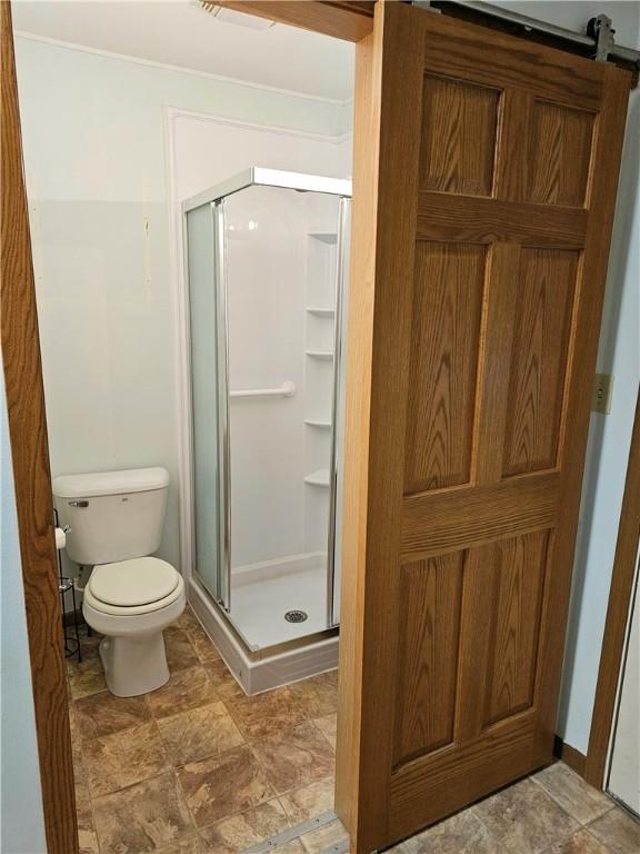 bathroom with a shower with door and toilet